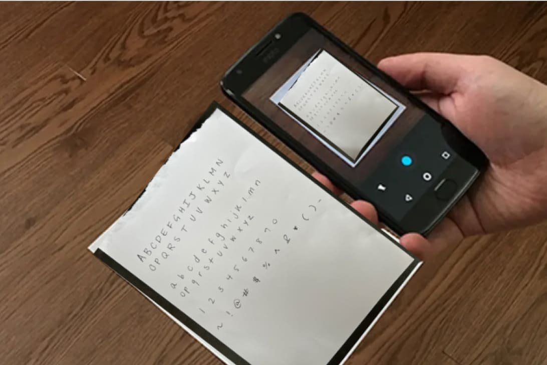 Image of a person taking a picture of the text he wrote on the page.